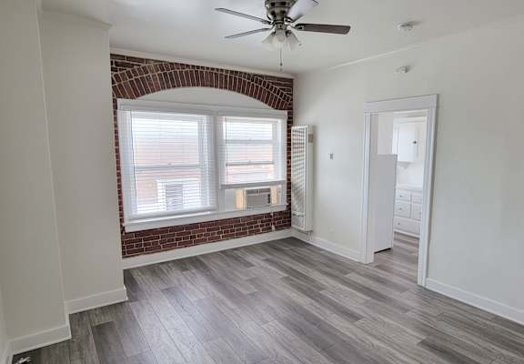 A room with a brick arched window and a ceiling fan.