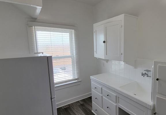 A white bathroom with a sink, mirror, and cabinet.