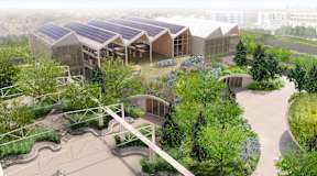 A modern building with solar panels on the roof is surrounded by greenery.