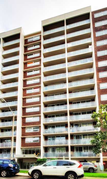 A large apartment building with cars parked in front.