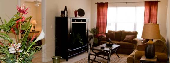 A living room with a fireplace, a couch, a chair, a coffee table, and a vase of flowers.