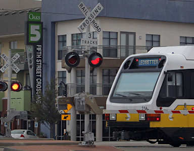 A train is stopped at a red light at the 5th Street Crossing.
