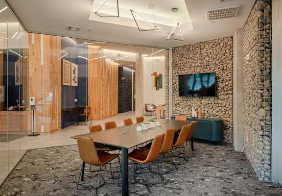 A conference room with a stone wall and a long table with chairs.