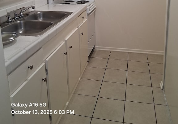 A kitchen with white cabinets and a white stove top oven.