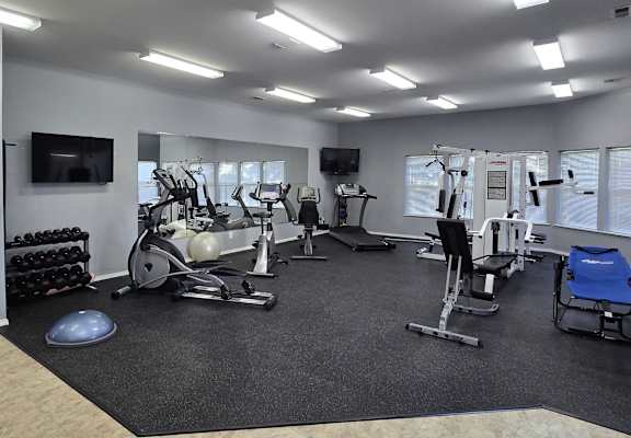 a gym with cardio equipment and a tv in a building