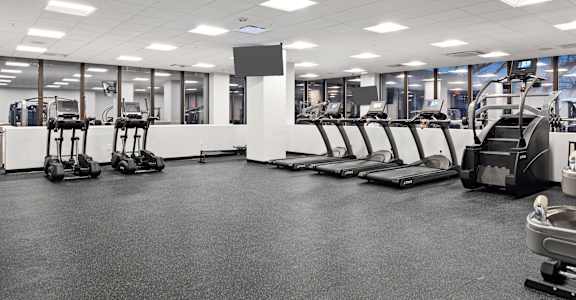 a large fitness room with cardio equipment and weights