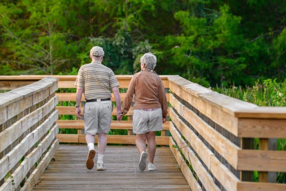 an older couple walking across a wooden bridge