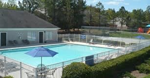 a resort style swimming pool in a backyard with a pool house and umbrellas