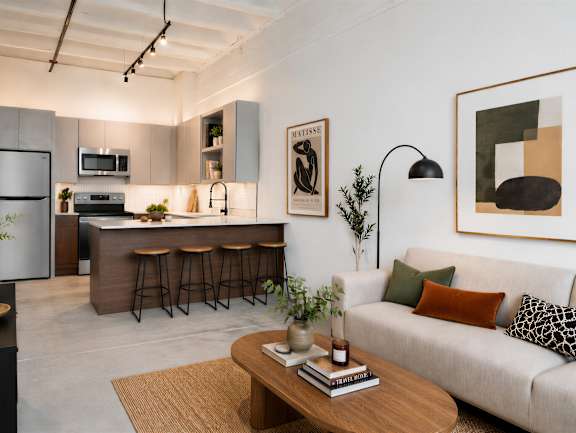 A modern living room with a kitchen area in the background.