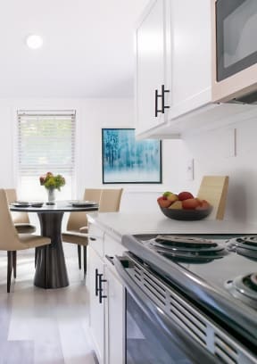 a kitchen with white cabinets and stainless steel appliances and a table with chairs