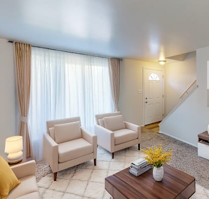 A living room with a couch, two chairs, a coffee table, and a painting on the wall.