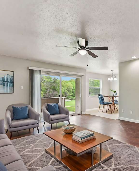 A living room with a grey couch, a coffee table, a television, and a ceiling fan.