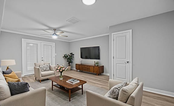 A living room with a ceiling fan, a couch, a chair, a coffee table, and a television.