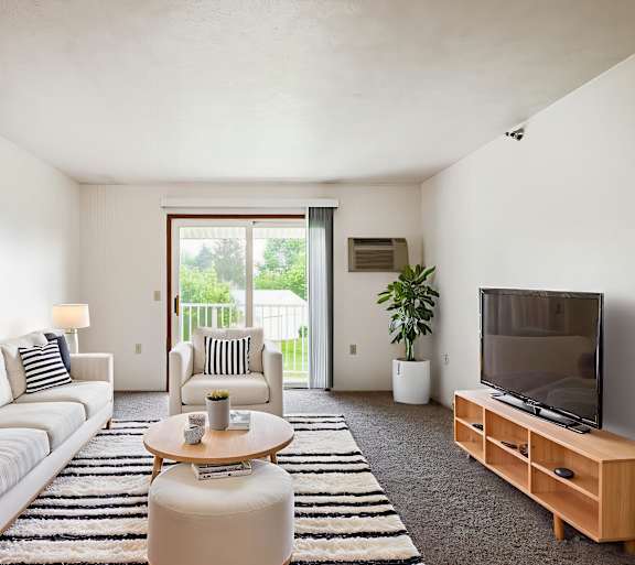 A living room with a white couch, a coffee table, and a television.