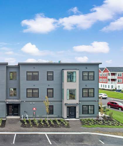 A modern apartment building with a parking lot in front.