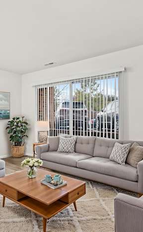 A living room with a grey couch, a coffee table, and a painting on the wall.