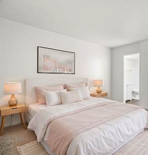 A bedroom with a large bed and two lamps on side tables.