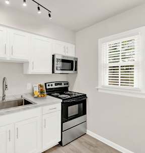a kitchen with white cabinets and black appliances and a sink