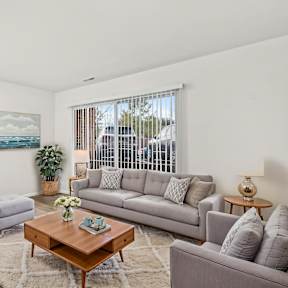 A living room with a grey couch, a coffee table, and a painting on the wall.