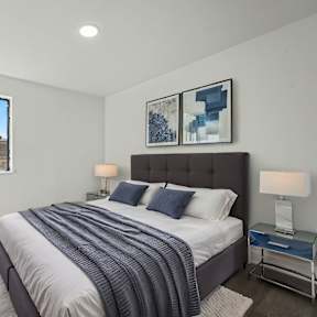 A bedroom with a large bed and a window overlooking a residential area.
