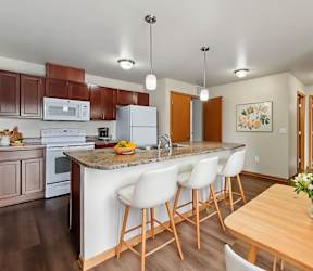 A kitchen with white cabinets and a bar area with stools at Melbourne Apartments, Des Moines, IA