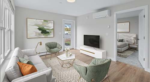 A living room with a grey couch, a green chair, and a white coffee table.