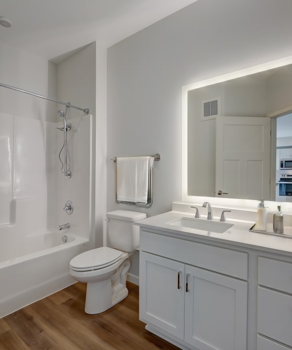 a white bathroom with a large mirror and a white toilet and sink