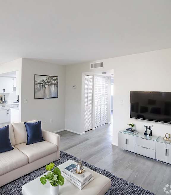 A living room with a white couch and a glass coffee table.