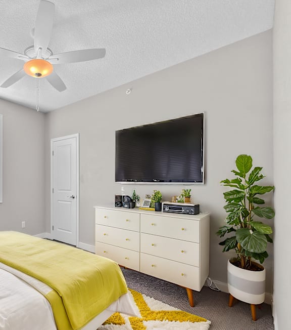 A bedroom with a bed, dresser, and a ceiling fan.