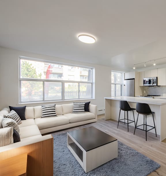 the living room and kitchen of an apartment with wood floors and white cabinets at 111 Cosburn, Ontario