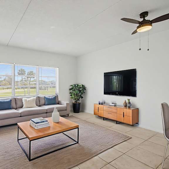 A living room with a sofa, a coffee table, a chair, and a flat-screen TV.