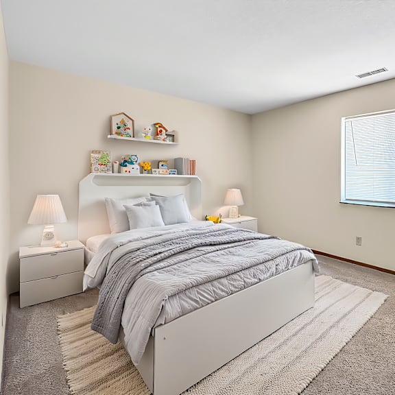 A bedroom with a large bed and a window with blinds.