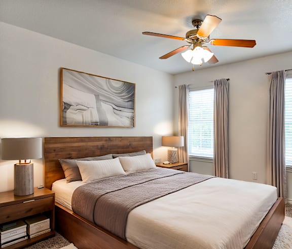 A bedroom with a large bed, a ceiling fan, and a potted plant.