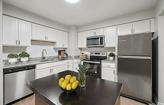 A kitchen with a black counter top and stainless steel appliances.