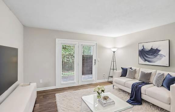 A living room with a white couch, a glass coffee table, and a painting on the wall.