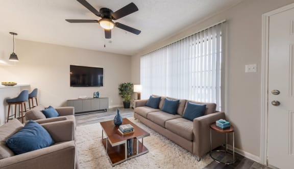 a living room with couches and a coffee table and a ceiling fan