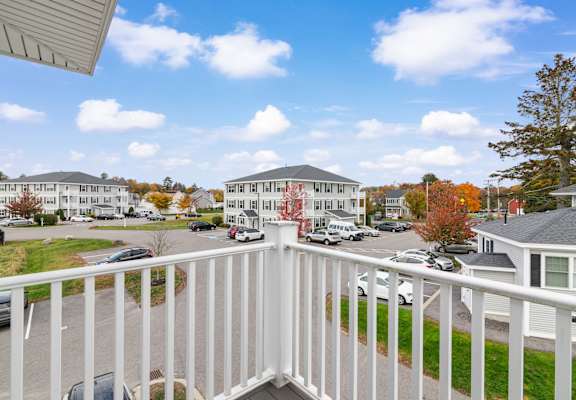 A white railing overlooks a parking lot and apartment buildings.