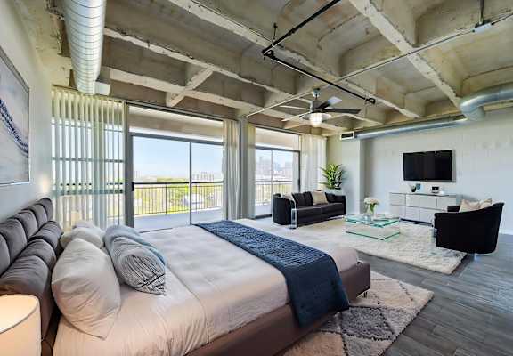 A bedroom with a large bed and a balcony overlooking the city.