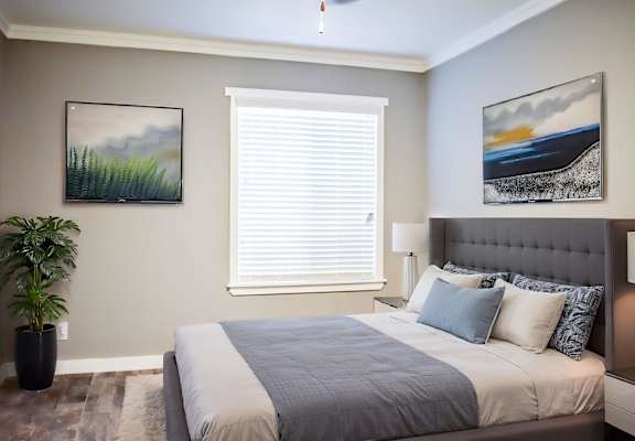 A bedroom with a large bed and two pictures on the wall.