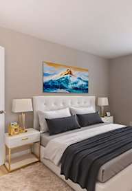 A bedroom with a large bed and a painting of a mountain on the wall.