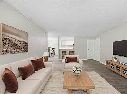 A living room with a white couch, a wooden coffee table, and a painting on the wall.