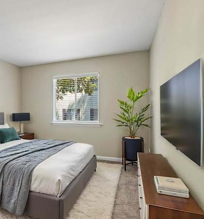 A bedroom with a bed, nightstand, and a painting on the wall.
