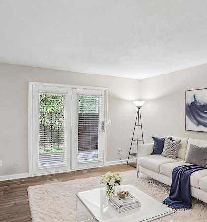 A living room with a white couch, a glass coffee table, and a painting on the wall.