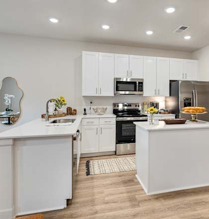A modern kitchen with white cabinets and appliances.