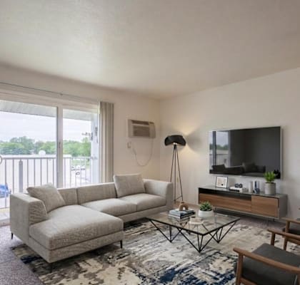 A living room with a white couch, a black floor lamp, a wooden coffee table, and a flat-screen TV mounted on the wall.
