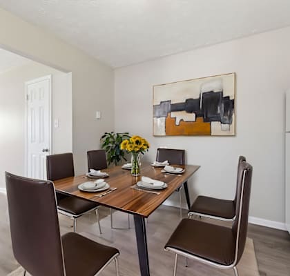 A dining room with a table set for two and a painting on the wall.