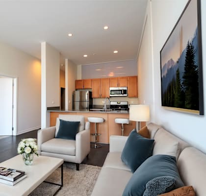 Spacious living room with open-concept kitchen at Highpoint Lincoln Park on Fullerton apartments in Chicago featuring island, stainless steel appliances, and granite countertops