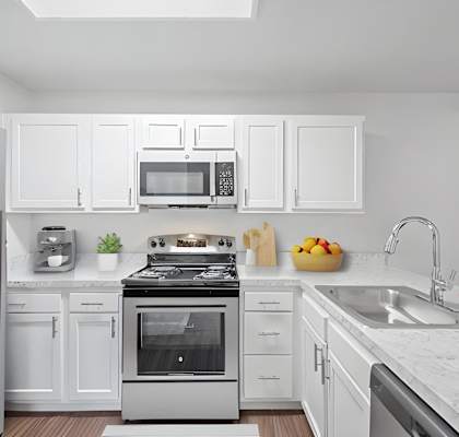 a white kitchen with stainless steel appliances and white cabinets