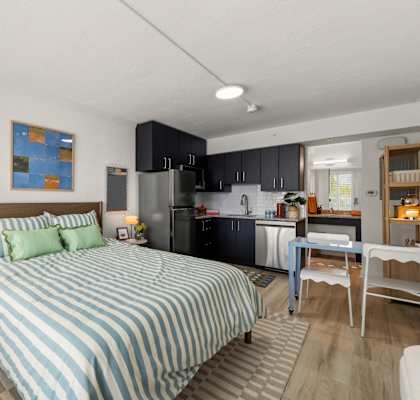 A bedroom with a bed, a desk, and a kitchen area.at The Teale New Haven Apartments, Melbourne, FL, 32904