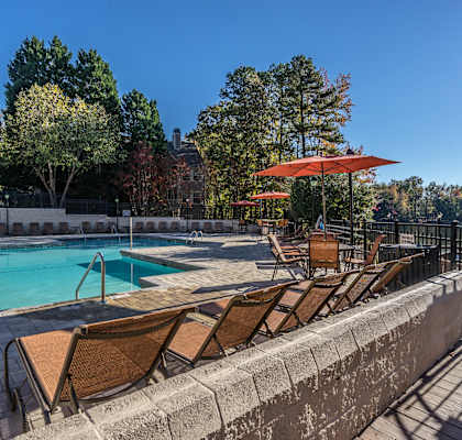 a swimming pool with chairs and umbrellas on a sunny day at Radbourne Lake Apartments, Charlotte North Carolina